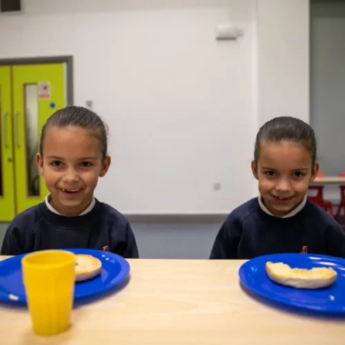 Photo of twin girls smiling at camera with bagels.