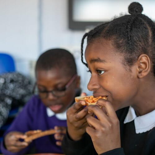 Two school children eating beans on toast.