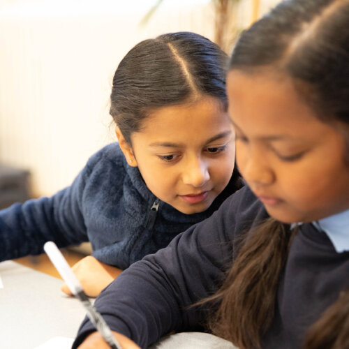 Two children doing schoolwork and colouring in.