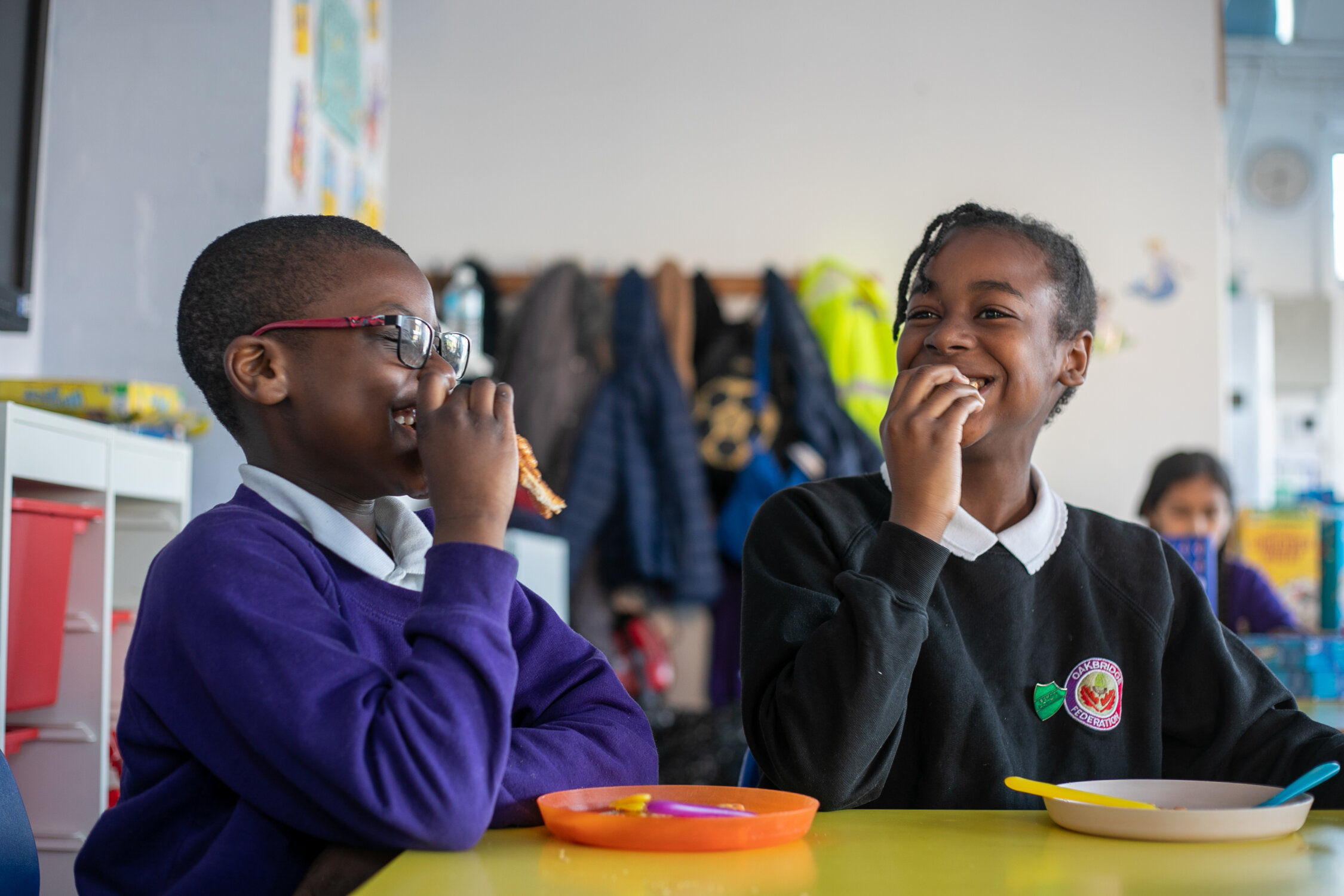 Two school children smiling while having breakfast