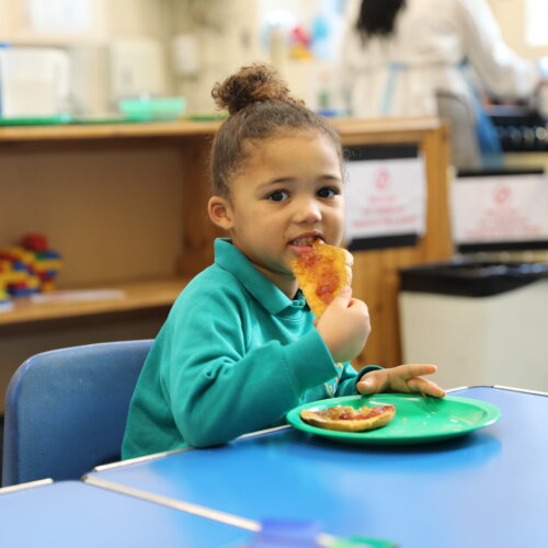 School child eating a piece of toast with jam.