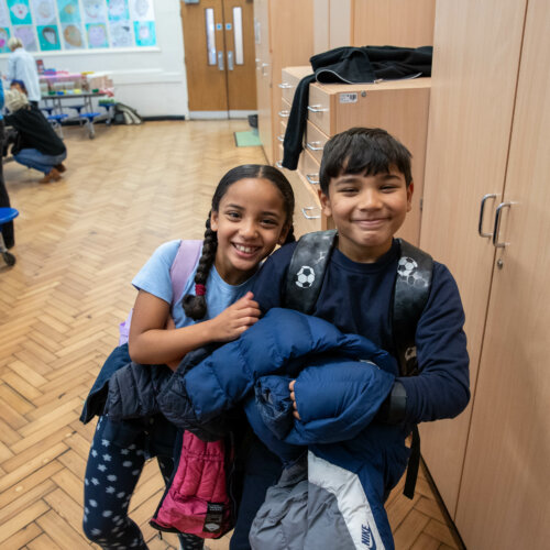 Two school children together and looking happy.