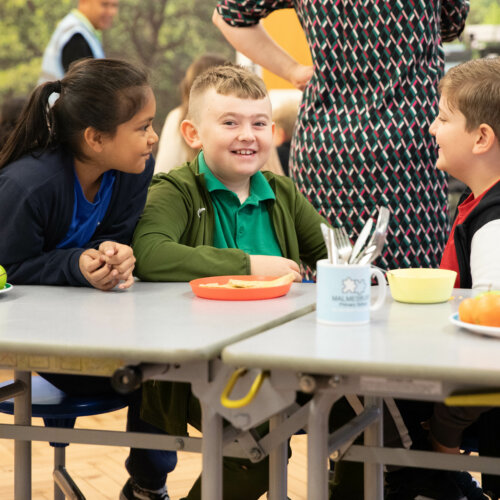 Three small children smiling and having breakfast