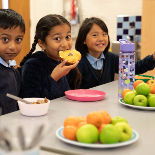 Three school children eating breakfast.