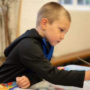 School child concentrating while painting.