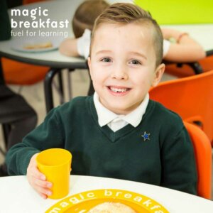 A picture of a boy holding a glass with breakfast in front of him for the Annual Report 2021-22