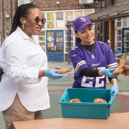 Two women handing out bagels