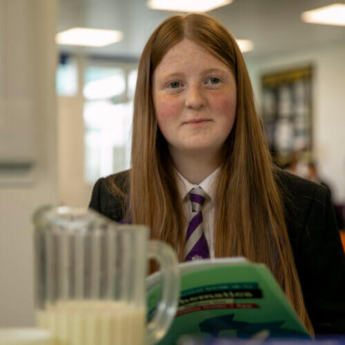 Image of a school child with long hair reading a book