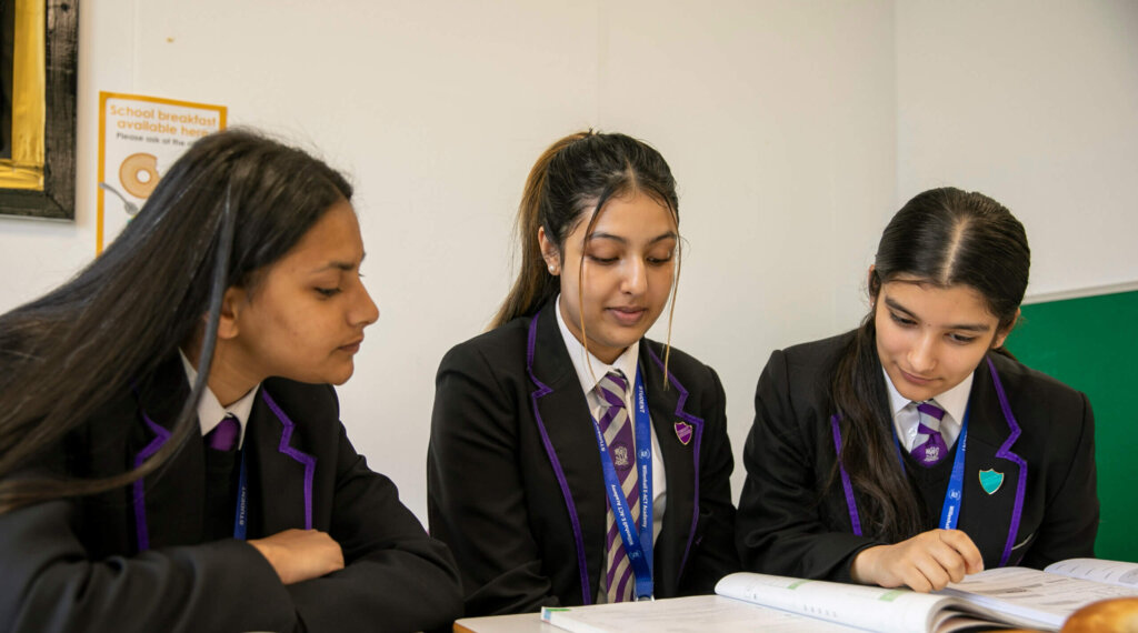 Three secondary school students look over their exam books