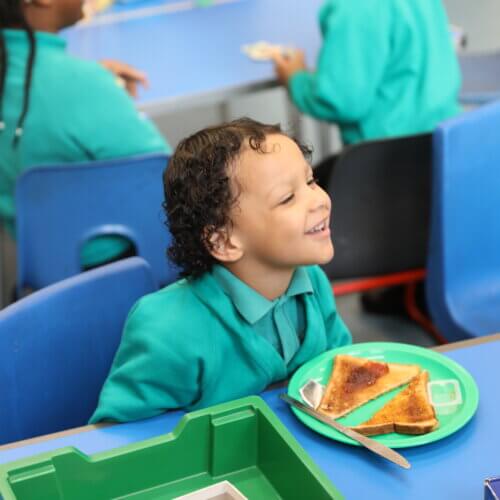 A child at a table with a plate of toast and jam in front of them