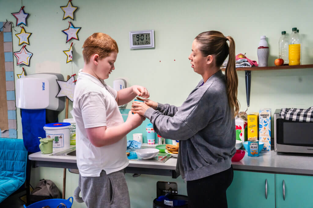 A 14 year old student at a Magic Breakfast school opens a tin of beans, helping school staff to prepare breakfast for his fellow learners.