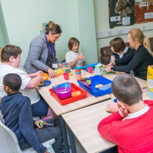 A group of students at an SEND school sit around the table to enjoy breakfast together