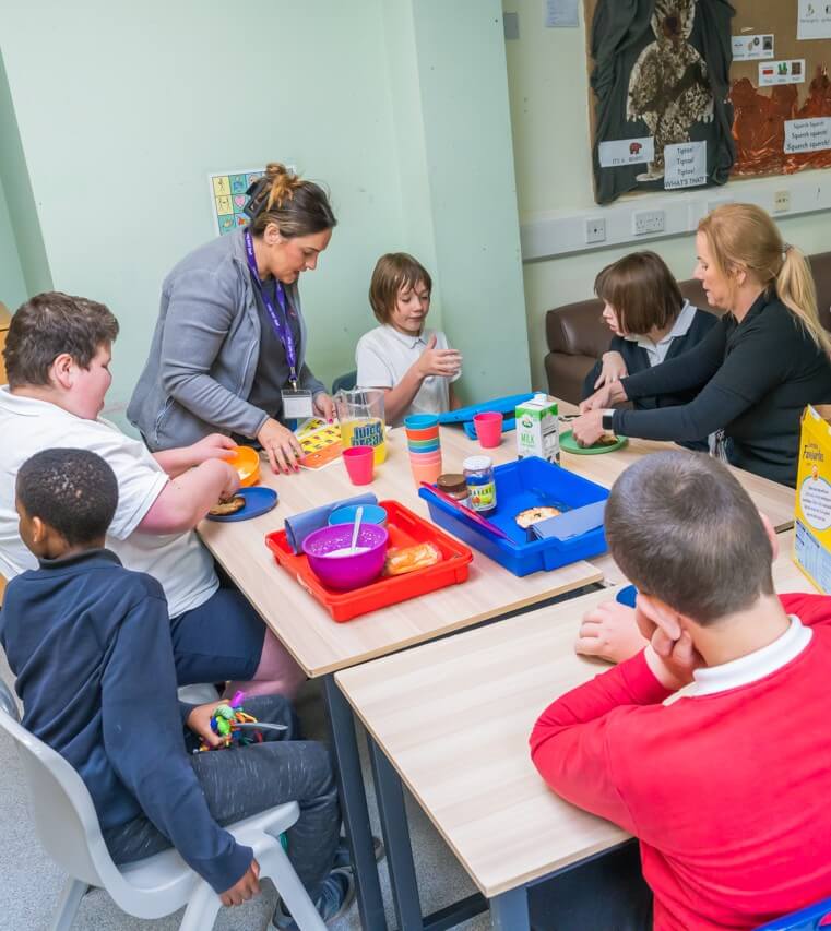 A group of students at an SEND school sit around the table to enjoy breakfast together