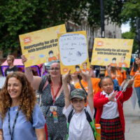 Children and school staff at a Magic Breakfast campaign holding placards.