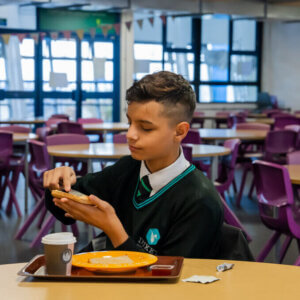 A secondary school student butters their toast in the school hub