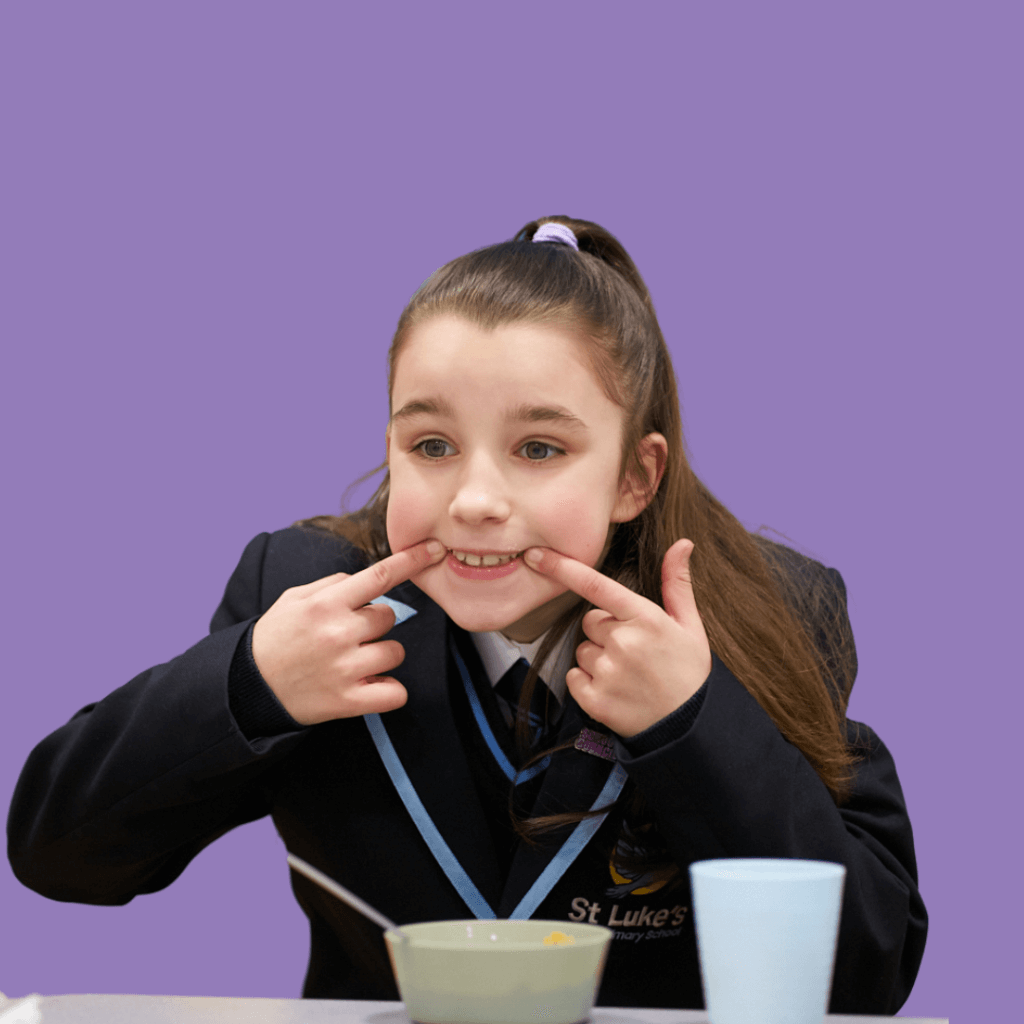 A Magic Breakfast student, aged 9, pulls a funny face while eating breakfast