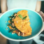 Egg omelette on a blue plate held by a woman